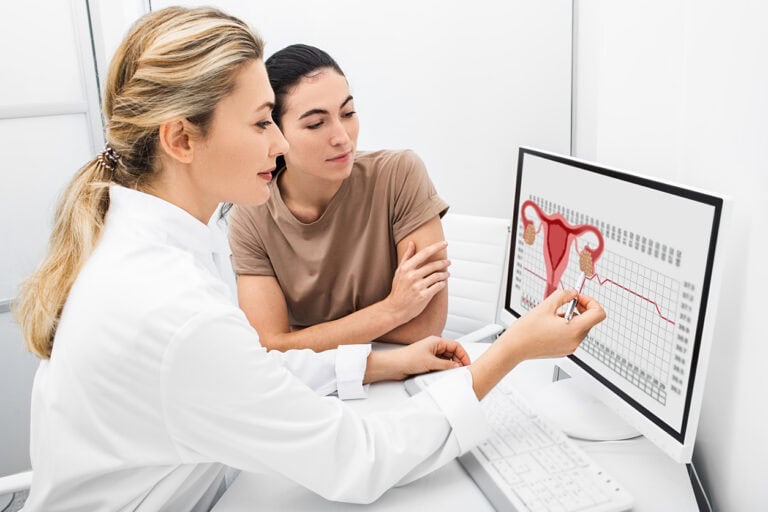 Female gynecologist talks to her female patient about the menstrual cycle.