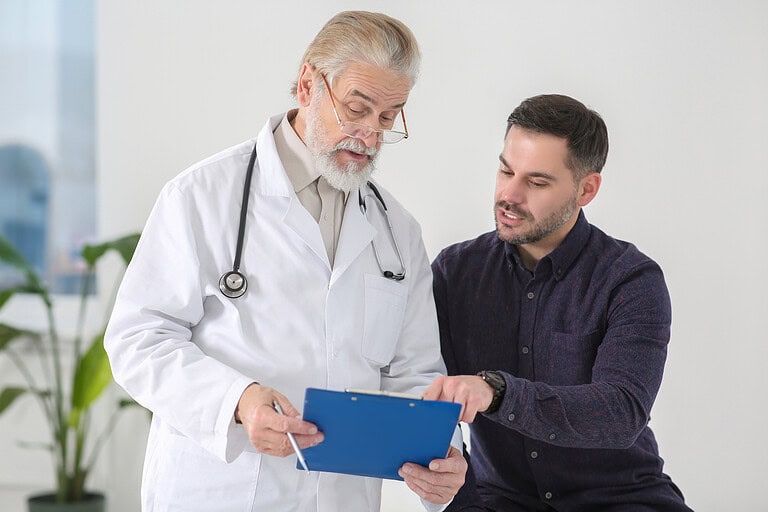 male patient and male doctor having a discussion in clinical setting.