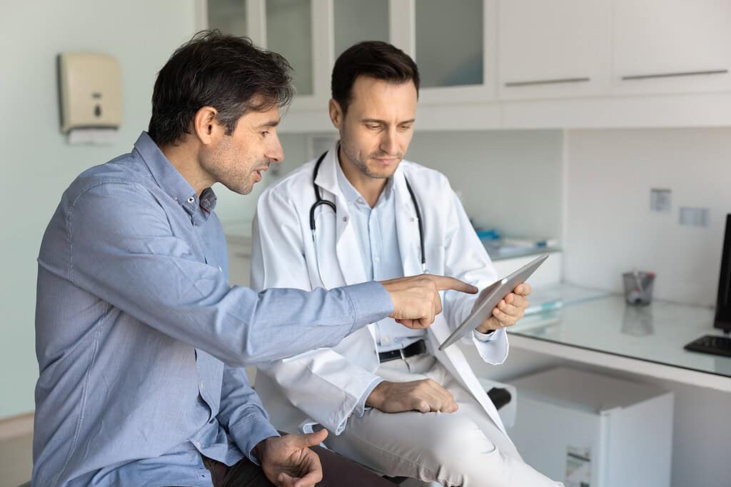 Image of patient asking his doctor questions. They are talking in an exam room.
